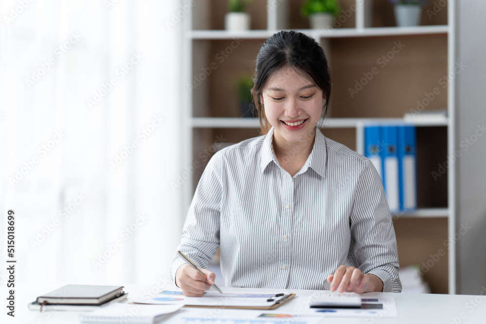 Portrait of an Asian young business Female working on report in her workstation.Business people employee freelance online report marketing e-commerce telemarketing concept. Portrait of an Asian young business Female working on report in her workstation.Business people employee freelance online report marketing e-commerce telemarketing concept.