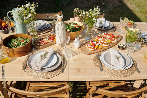 Wall Mural Served wooden table with homemade food, drinks, glasses, plates, wildflowers and