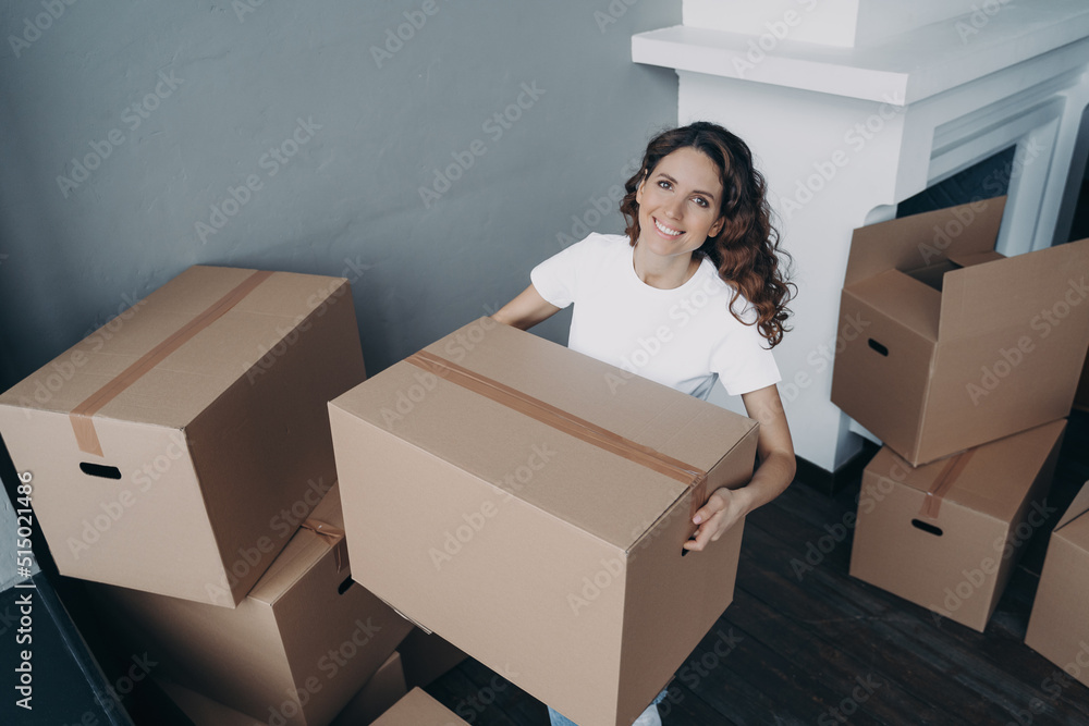 Attractive european girl in white t-shirt leaving house. Lady packing and carrying cardboard boxes.