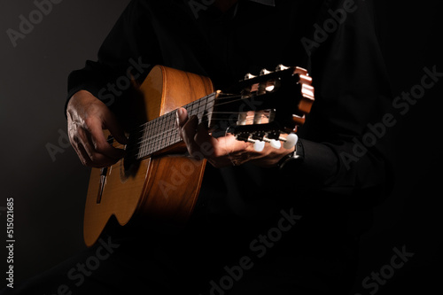 Spanish classical guitar and guitarist's hands up close on a black background with copy space