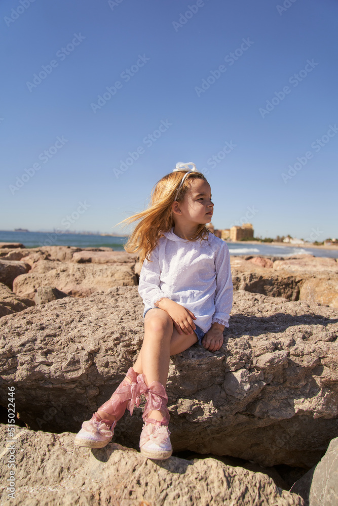 portrait of a little girl with a shirt sitting on rocks