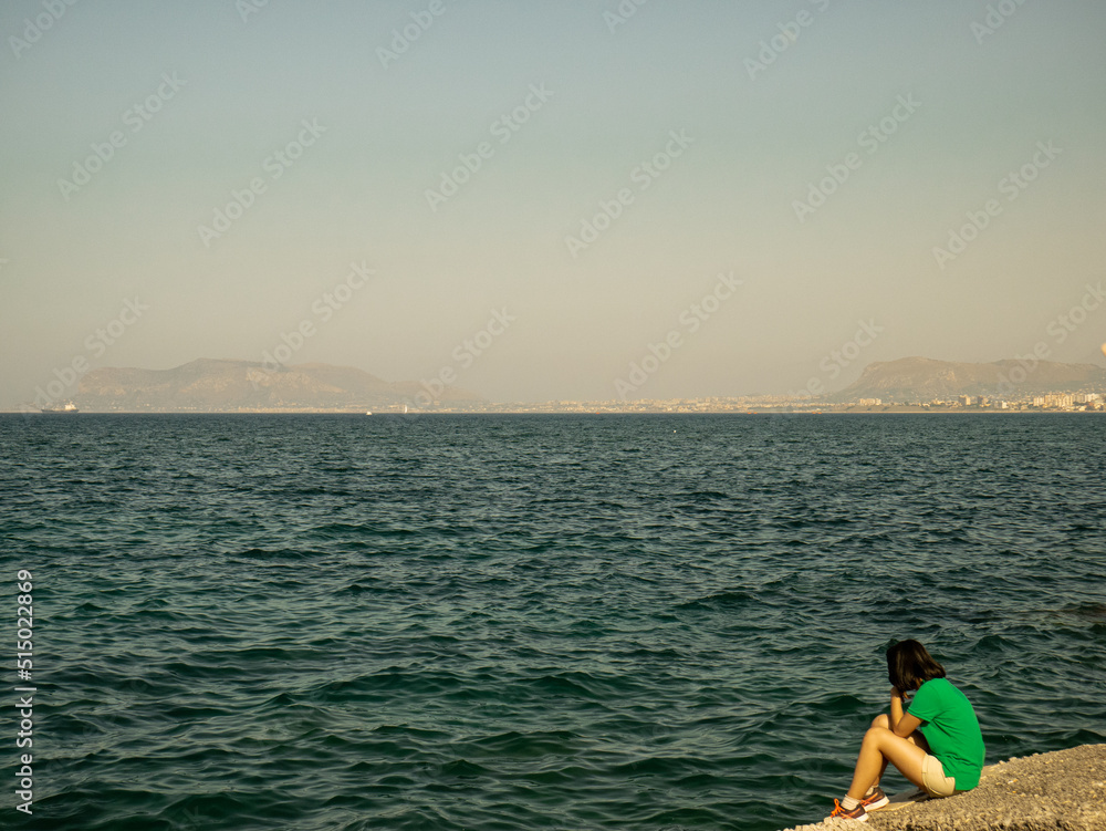 Girl with green shirt staring at the sea