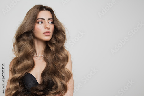 Portrait of a beautiful girl with luxurious curly long hair. White background.