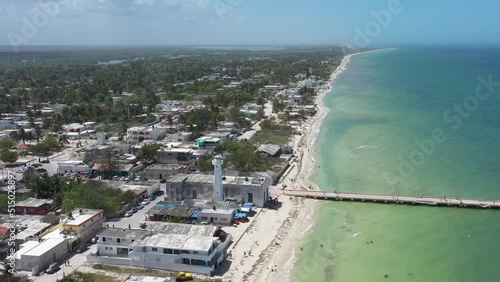 High aerial pull away from lighthouse, fishing pier, tropical village. photo