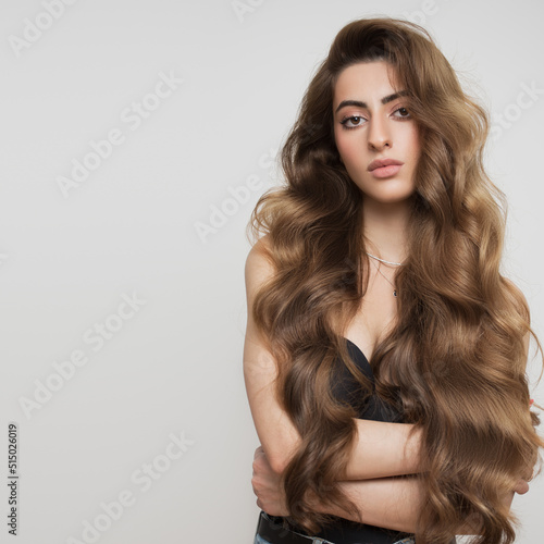 Portrait of a beautiful girl with luxurious curly long hair. White background.