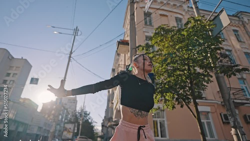 Young woman shows moves of hip-hop dance at back sunset