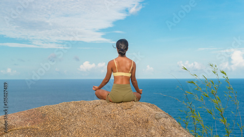 Beautiful asian woman in sportswear doing yoga on seaside mountain peak after trekking  Travel and meditation concept.
