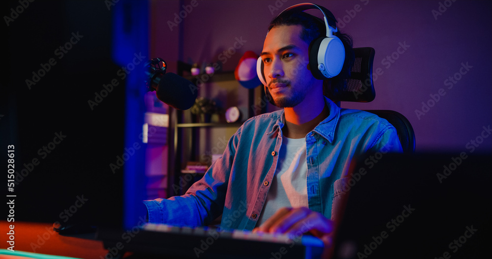 Happy asia guy gamer wear headphone participation play video game colorful neon lights computer in living room at night modern house. Esport streaming game online, Home quarantine activity concept. Happy asia guy gamer wear headphone participation play video game colorful neon lights computer in living room at night modern house. Esport streaming game online, Home quarantine activity concept.