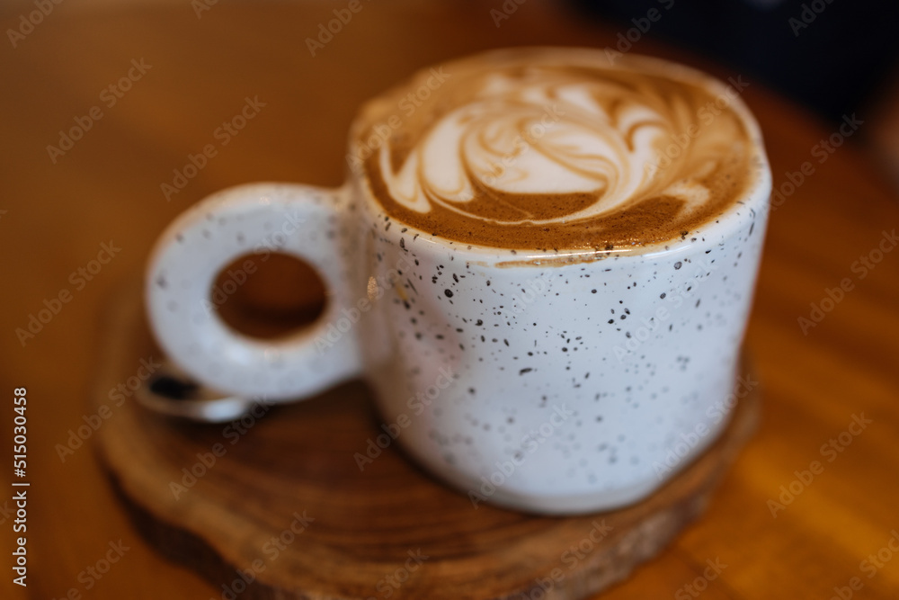 Cappuccino coffee in light cup on a wooden table in cafe. Selective sharpness Cappuccino coffee in light cup on a wooden table in cafe. Selective sharpness