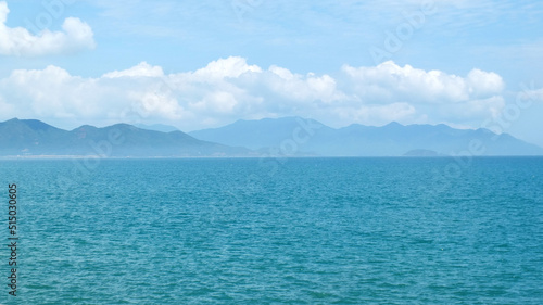  Sea with turquoise color water and blue sky with white clouds and the outlines of mountains on the horizon. Travelling , tourism, vacation near the sea concept. 
