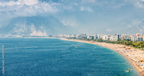 Fototapeta Naklejka Na Ścianę i Meble -  Aerial view of scenic and popular Konyaalti beach in Antalya resort town. Majestic mountains with haze in the background. Vacation and holiday in Turkiye