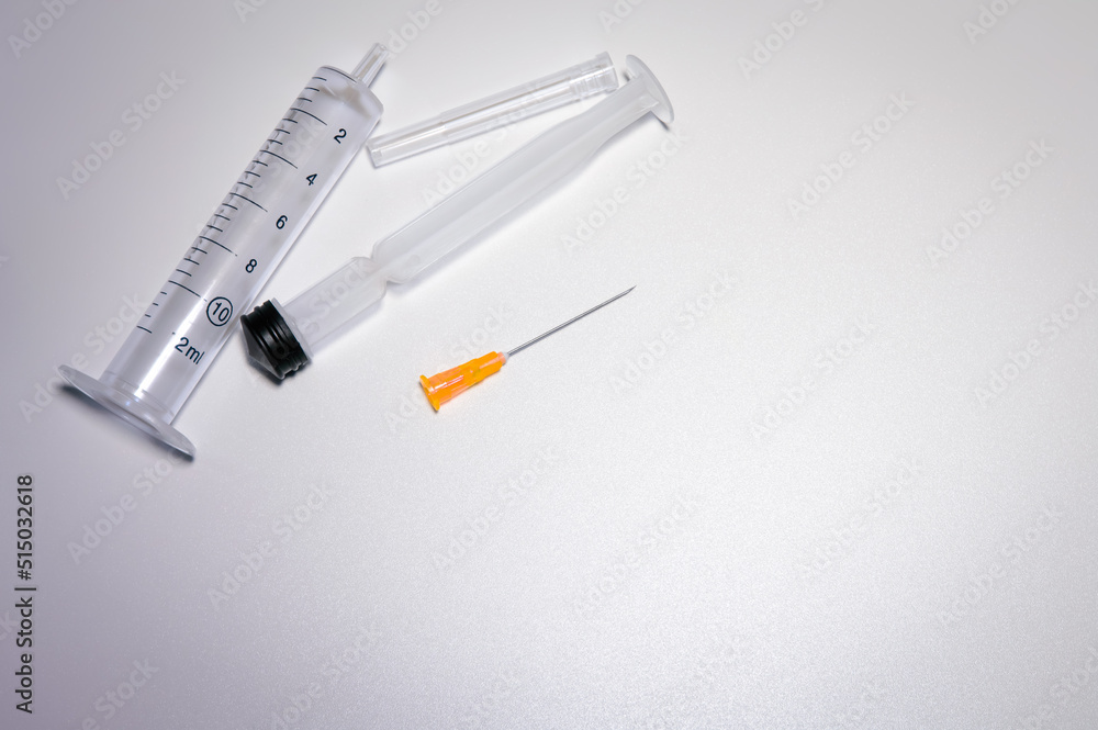 Parts of a medical syringe with a bright orange needle. Space for text. Pharmaceutical images with copy space. Parts of a medical syringe with a bright orange needle. Space for text. Pharmaceutical images with copy space.