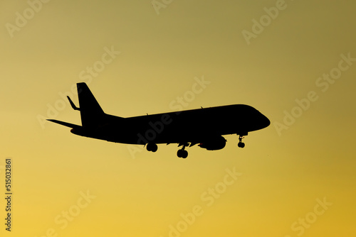 Airplane silhouette in sunset orange sky.