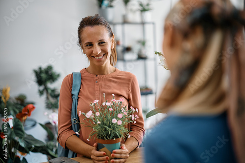 Happy woman buying flowers and communicating with florist at floral shop.