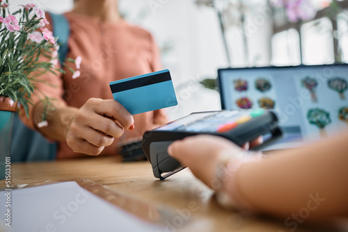 Close up of woman pays with credit card at flower shop.