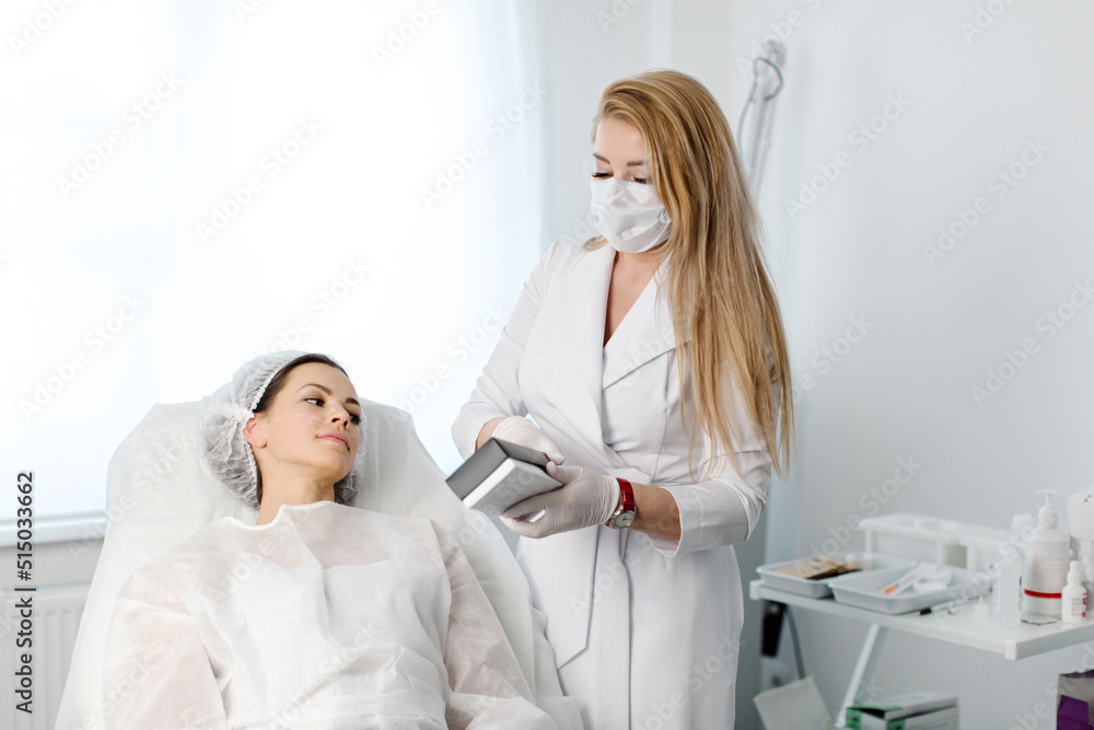 Obraz premium Experienced female cosmetologist gives consultation to a young female patient lying on a sofa in a cosmetologist's office of an aesthetic clinic. High quality photo