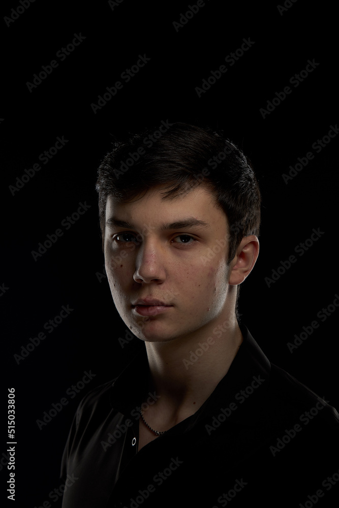Portrait of a brunette teenager, in a black shirt on a navy blue background. Portrait of a brunette teenager, in a black shirt on a navy blue background.