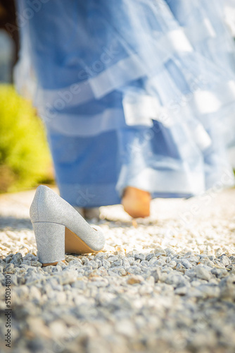 Shot of a girl with a beautiful fairytale blue prom dress left her shoe like Cinderella and is walking away from it.