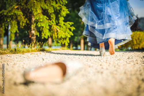 Shot of a girl with a beautiful fairytale blue prom dress left her shoe like Cinderella and is walking away from it.