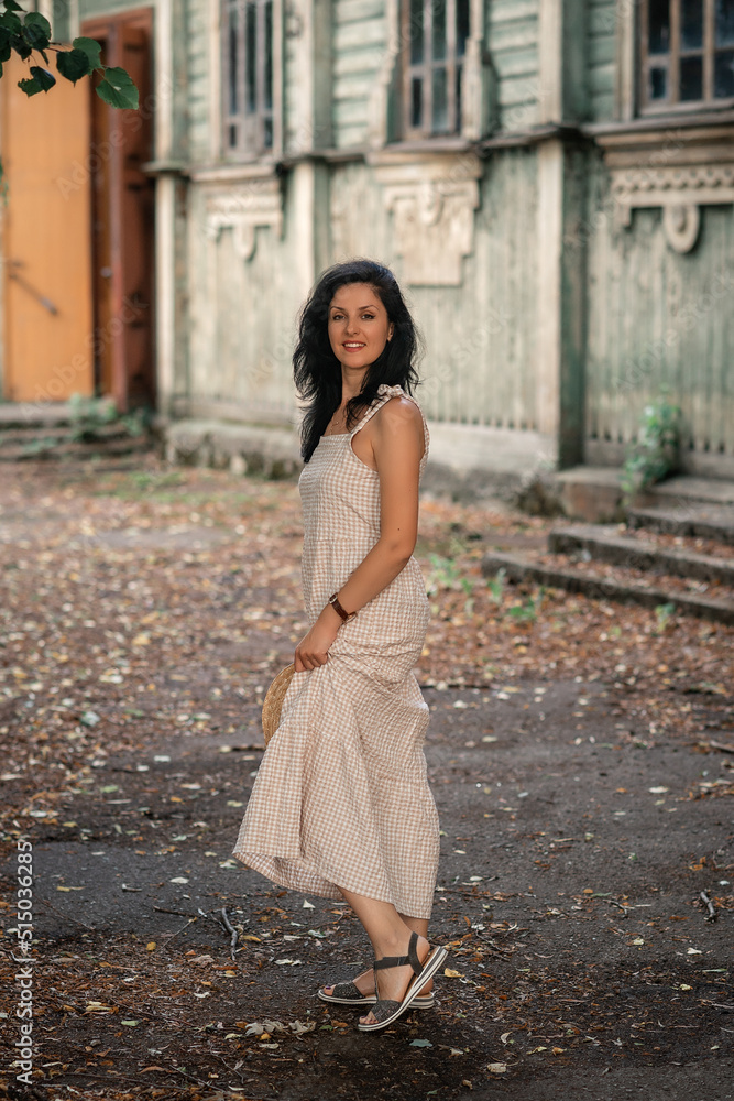 woman in beige dress is standing  behind the wooden wall