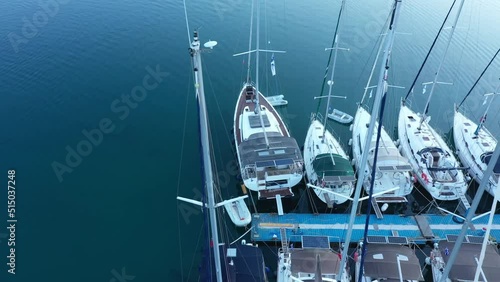 Aerial top-down view of docked sailboats. Top down view of yachts in the marina. Sailboats and regular Boats moured in Palairos Marina Greece. Sailboats and catamarans anchored in the harbour. photo