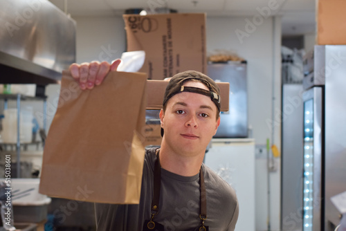 Restaurant kitchen employee holding paper bag take out food order photo