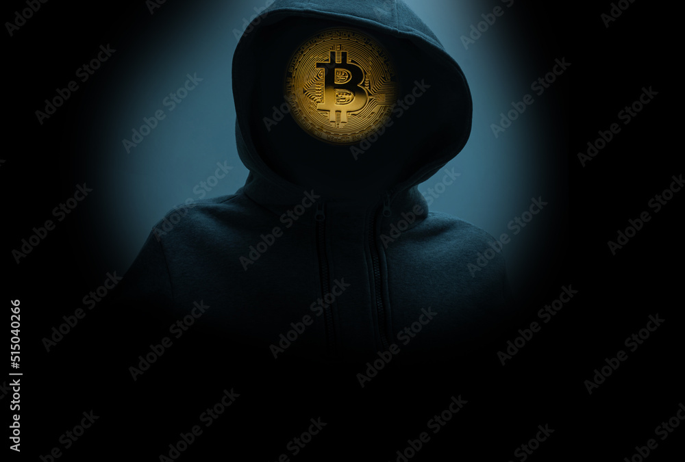 Man without a face in a hood holds a luminous bitcoin icon on a dark background. Man without a face in a hood holds a luminous bitcoin icon on a dark background.