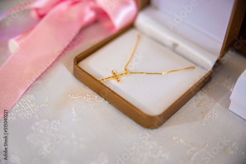 A little golden cross in a jewelry box prepared for a baby's christening baptism ceremony. High quality photo