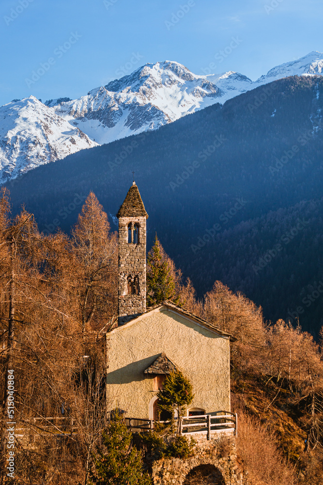 The church of San Clemente, in the mountains of Val Camonica with the setting sun, near the town of Vezza d'Oglio, Italy - January 2022.