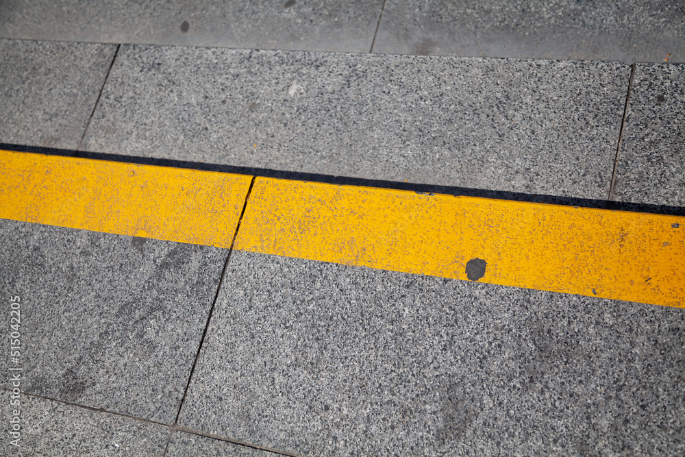 Fototapeta premium Yellow stripe on step of stone staircase