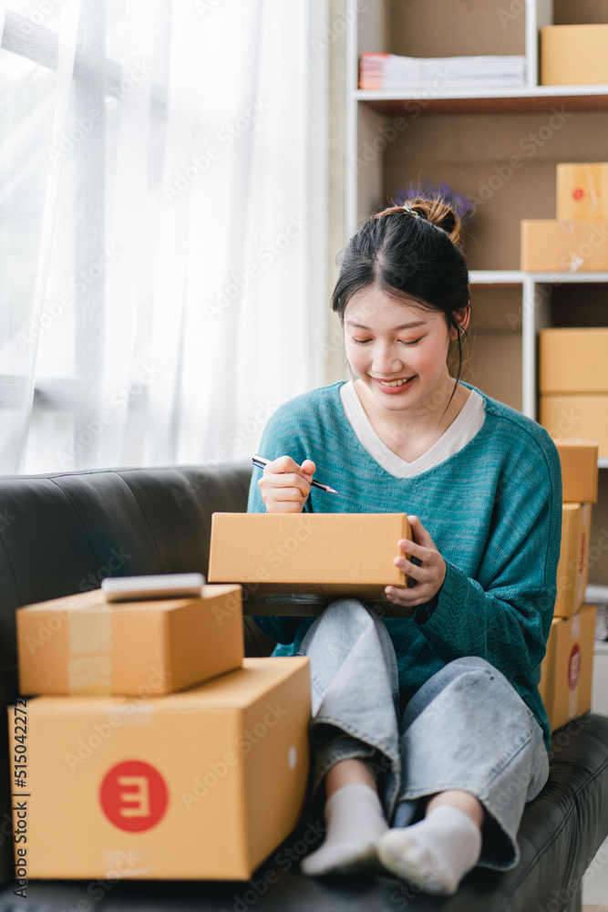 Portrait of a small business startup, SME owner, female entrepreneur, working, unboxing, checking orders online. To prepare to pack boxes for sale to SME customers online business ideas Portrait of a small business startup, SME owner, female entrepreneur, working, unboxing, checking orders online. To prepare to pack boxes for sale to SME customers online business ideas