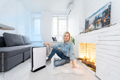 woman turning on and using the modern air purifier in the living room, air purifier is a popular appliance - household electricity. Air purifier can help to purify the air. photo