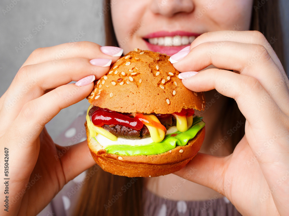 The girl has a burger close up. Sweet burger dessert, cream cake. The original recipe. Small burgers on the buffet table. Children's Birthday table. Copy space. Close up. Candy bar. Colorful dessert. The girl has a burger close up. Sweet burger dessert, cream cake. The original recipe. Small burgers on the buffet table. Children's Birthday table. Copy space. Close up. Candy bar. Colorful dessert.