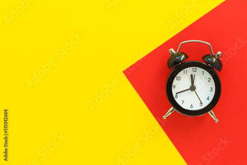 Mini alarm clock on red-yellow background. Deadline, planning for business meeting or travel planning concept. Flat lay, top view with copy space.