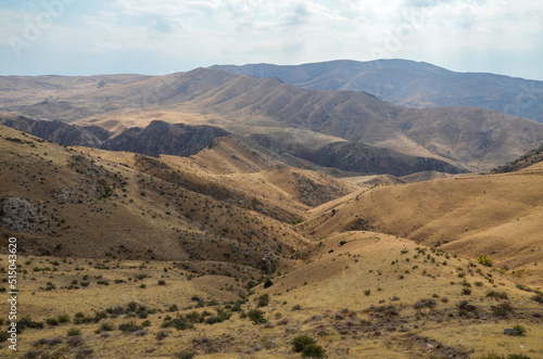 Autumn landscape of gentle slopes of mountainous terrain covered with trees and dry grass. Caucasus Mountains, Armenia 