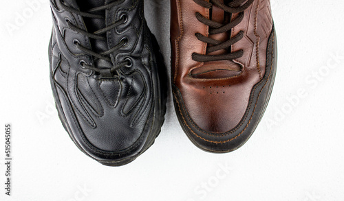 Black and brown leather men's shoes pair. Black low shoes, men's sneakers top view on a white background. Shoes concept.