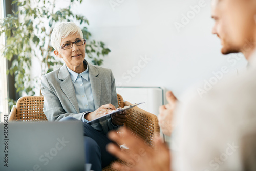 Konstfotografi Mature financial consultant advising her clients during meeting in the office
