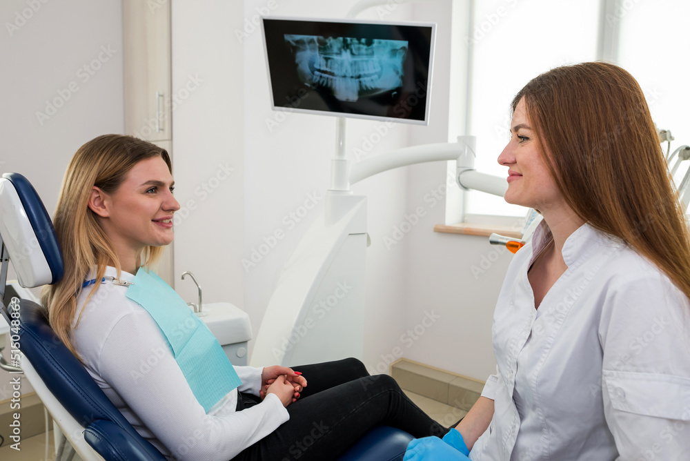 © Tania - She is sitting in the dentist's chair. The dentist explains and advises the patient.