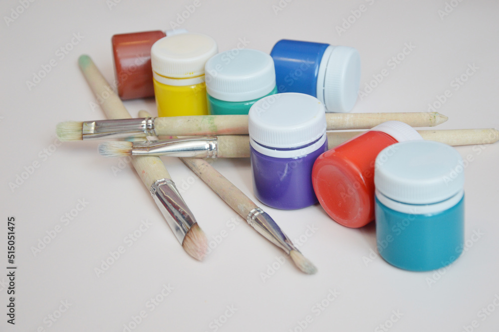 Artistic jars with multi colored gouache paints and brushes, close up. Working materials for drawing, creativity, hobby. Artistic jars with multi colored gouache paints and brushes, close up. Working materials for drawing, creativity, hobby.