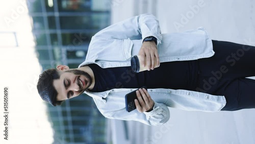 Portrait mode of smiling young attractive bearded man walking use smartphone look around at city center. Handsome man messagen stylish. Employment technology. photo