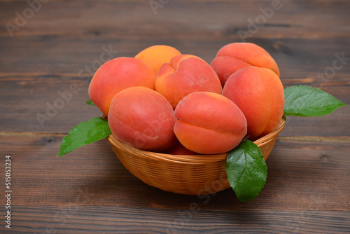 ripe apricots in a basket on a wooden background close up