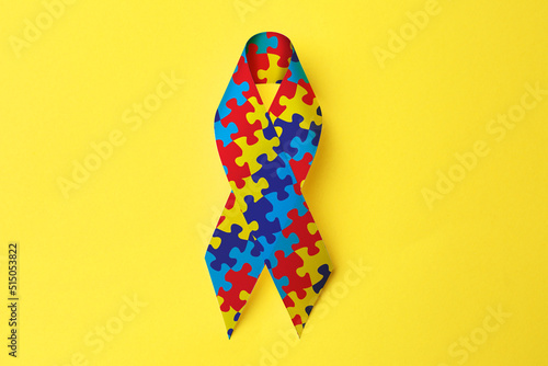World Autism Awareness Day. Colorful puzzle ribbon on yellow background, top view