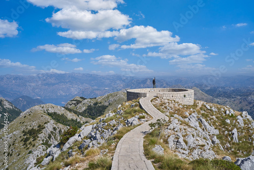 Tourist at the peak of the mountain reached the goal and raised his hand up in happiness in Lovcen, Montenegro