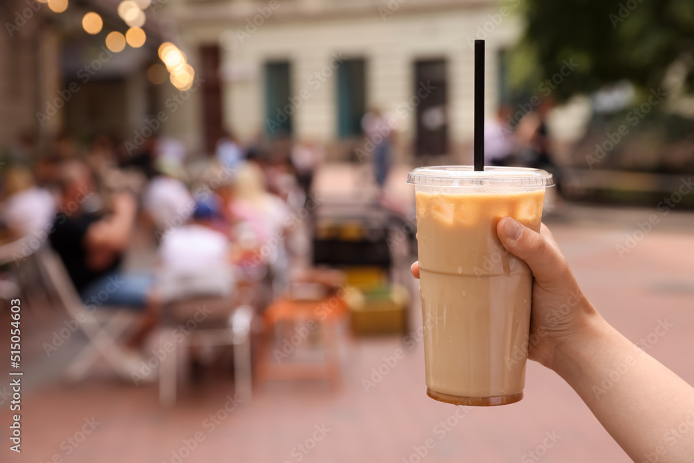 Woman holding takeaway plastic cup with cold coffee drink outdoors, closeup. Space for text Woman holding takeaway plastic cup with cold coffee drink outdoors, closeup. Space for text