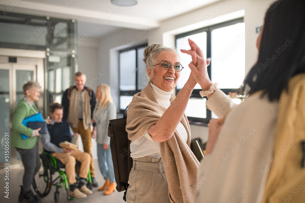 Φωτογραφία Happy senior women students meeting high fiving in corridor at university