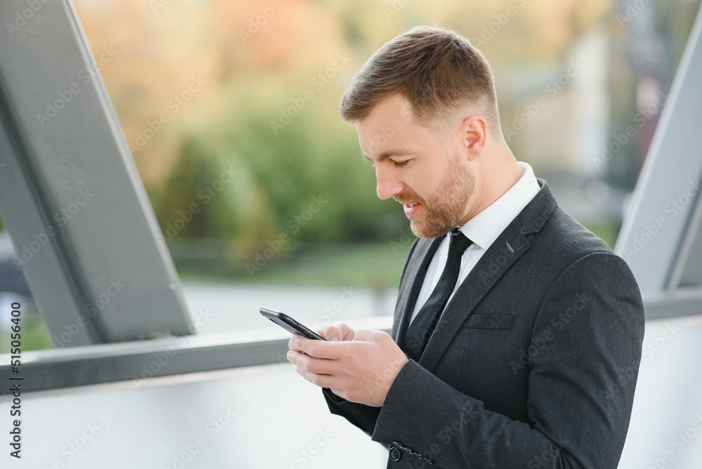 Businessman using smartphone in covered walkway. Businessman using smartphone in covered walkway.