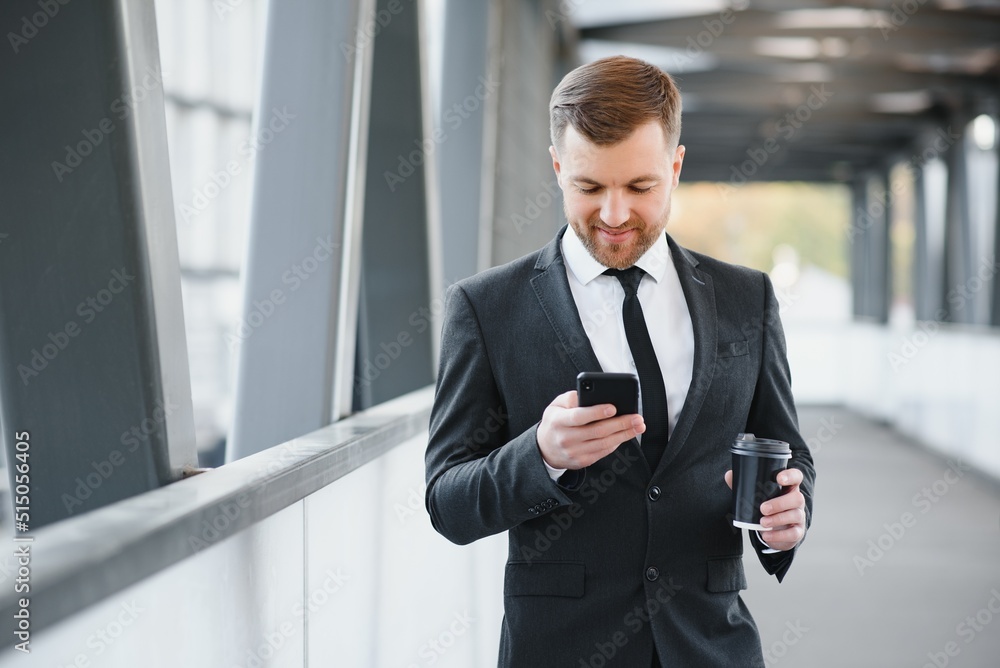 Confident young businessman using cell phone and drinking coffee in the city Confident young businessman using cell phone and drinking coffee in the city