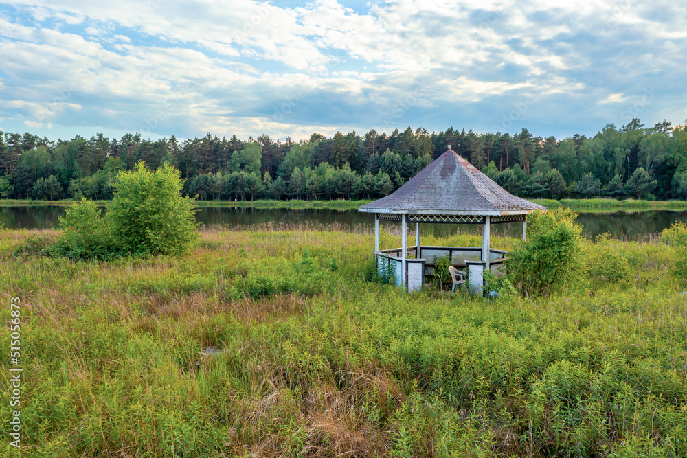 Wooden gazebo overgrown with grass, outdoor recreation, summer landscape Wooden gazebo overgrown with grass, outdoor recreation, summer landscape