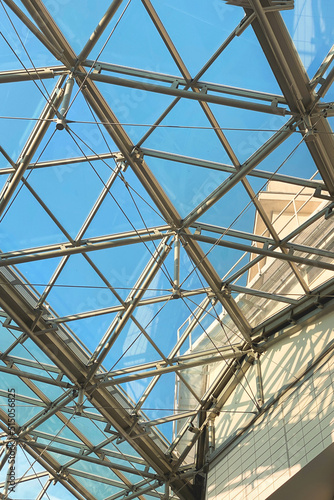 Geometric metal structure with glass, ceiling in a shopping center against the sky