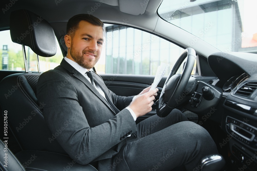 Always in a hurry. Handsome young man in full suit smiling while driving a car. Always in a hurry. Handsome young man in full suit smiling while driving a car.